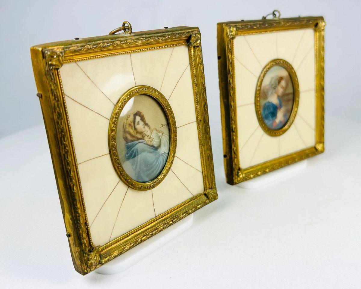 Pair of 19th century hand-painted miniature portraits in gilt frames with ivory-style panel insets. Depicting devotional female figures, one in prayer and one cradling a child. Original rectangular frames with oval portrait centers, fine detail and patina.
