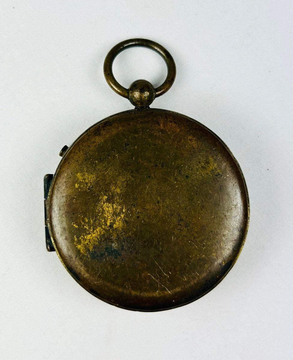 Back view of an antique French pocket compass showing smooth brass casing and natural age patina.