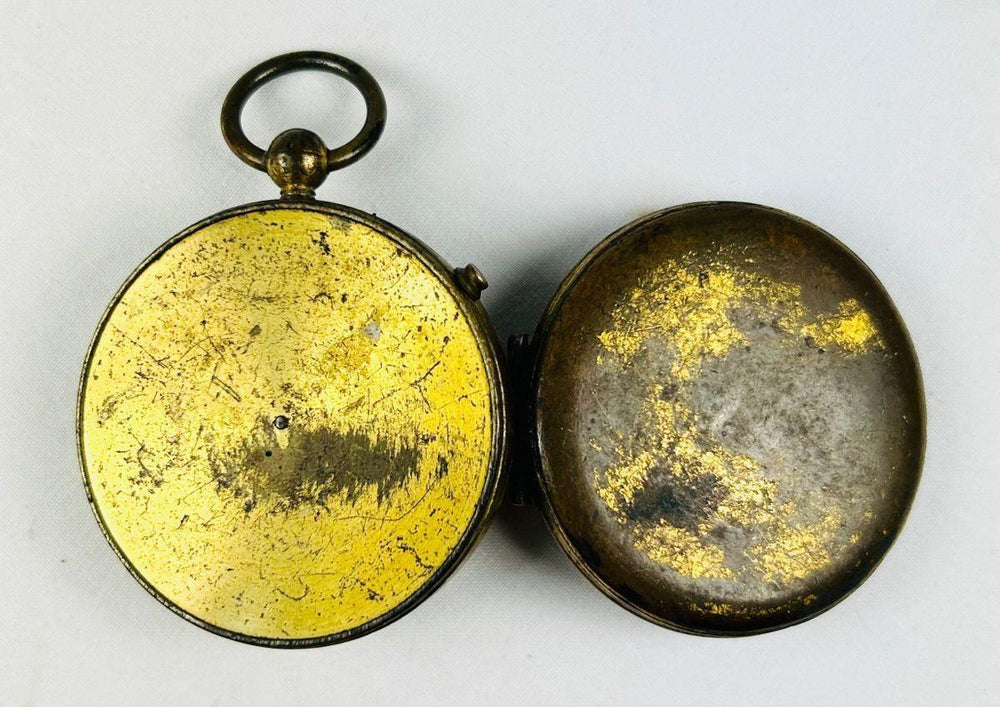 Antique French pocket compass photographed open to display dial, needle, and azimuth scale.