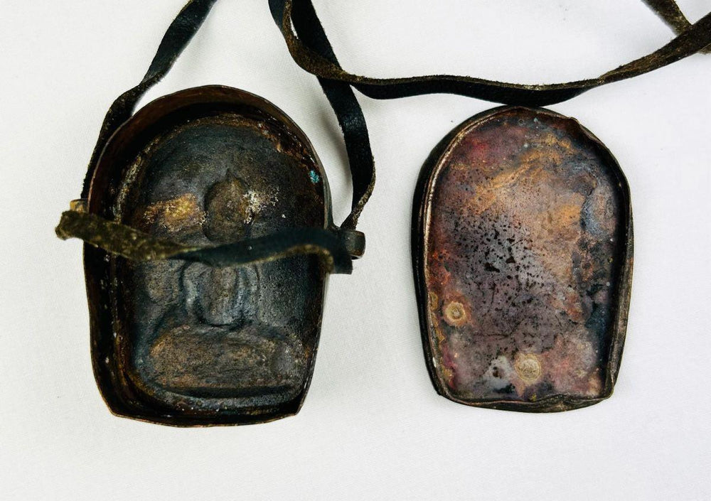 Tibetan Buddhist amulet box displayed on neutral background showing devotional details.