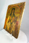 Side view of an 18th-century Russian Orthodox icon of a saint holding a Gospel book, hand-painted on an aged wooden panel.