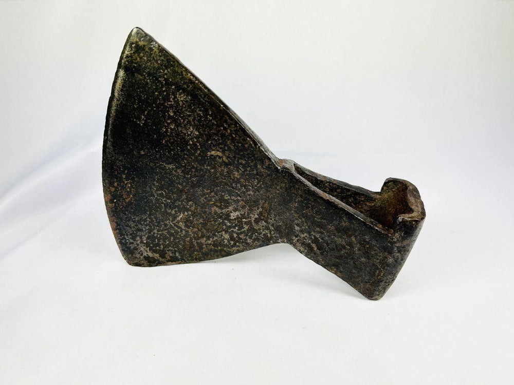 Close-up of 18th-century iron axe head surface texture and maker’s punch mark.