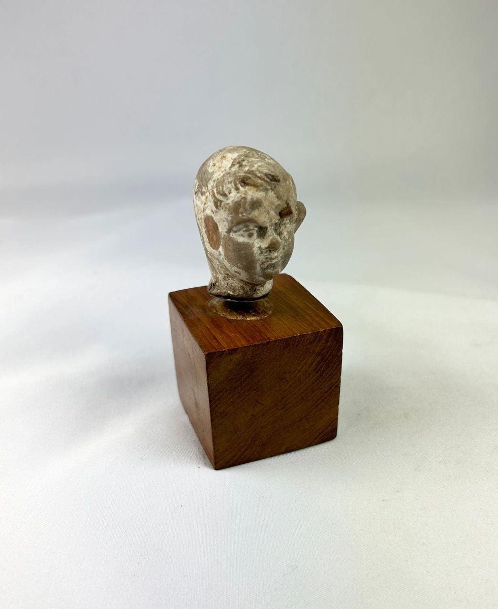 Ancient terracotta boy’s head showing youthful facial features and serene expression.
