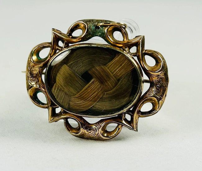 Front view of a Victorian mourning brooch with gold-plated frame and hairwork center.