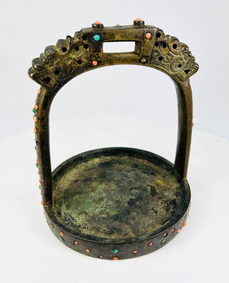 Side profile of Tibetan bronze stirrup with decorative gemstone settings and engraved details.