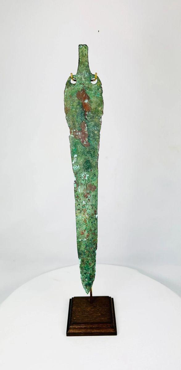 Back of Bronze Age Caspian blade showing drilled perforations and aged patina on custom display stand.