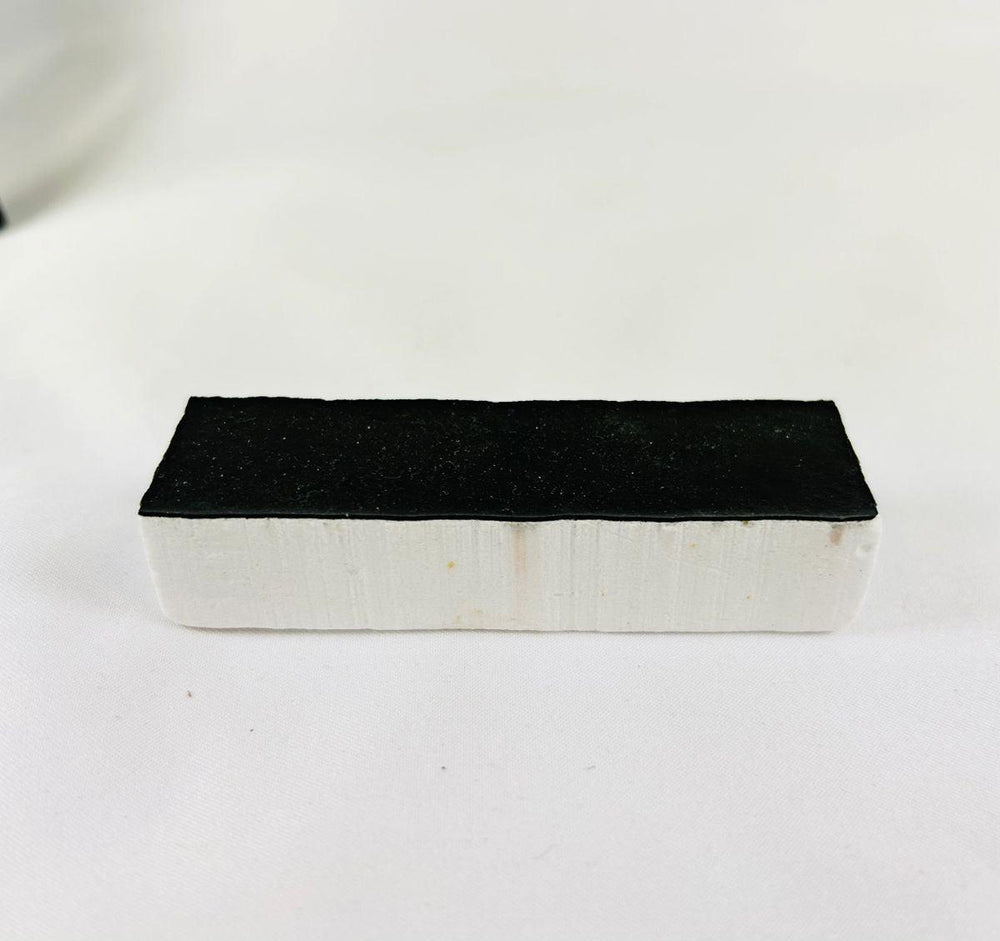 Authentic NASA Space Shuttle Thermal Protection System (TPS) tile from the 1980s, made of silica-based ceramic with black Reaction Cured Glass coating, used for reentry heat resistance, preserved in NASA-issued display case.