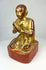Three-quarter angle of gilded Burmese monk statue, highlighting prayer posture and lacquer finish.