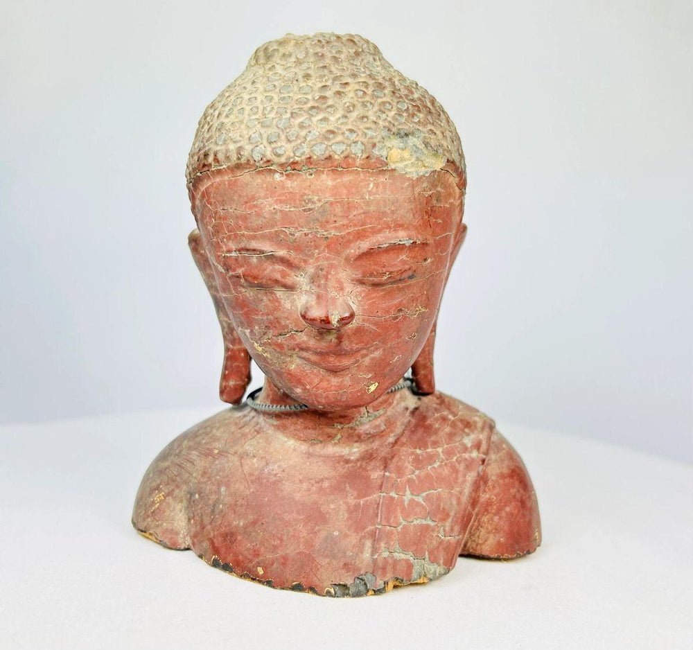 Detailed shot of wooden Buddha bust showing textured surface and devotional craftsmanship.