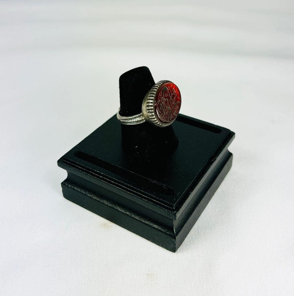 Ancient Near Eastern carnelian intaglio ring, 1st millennium BCE, red carnelian with detailed engravings, displayed on black stand