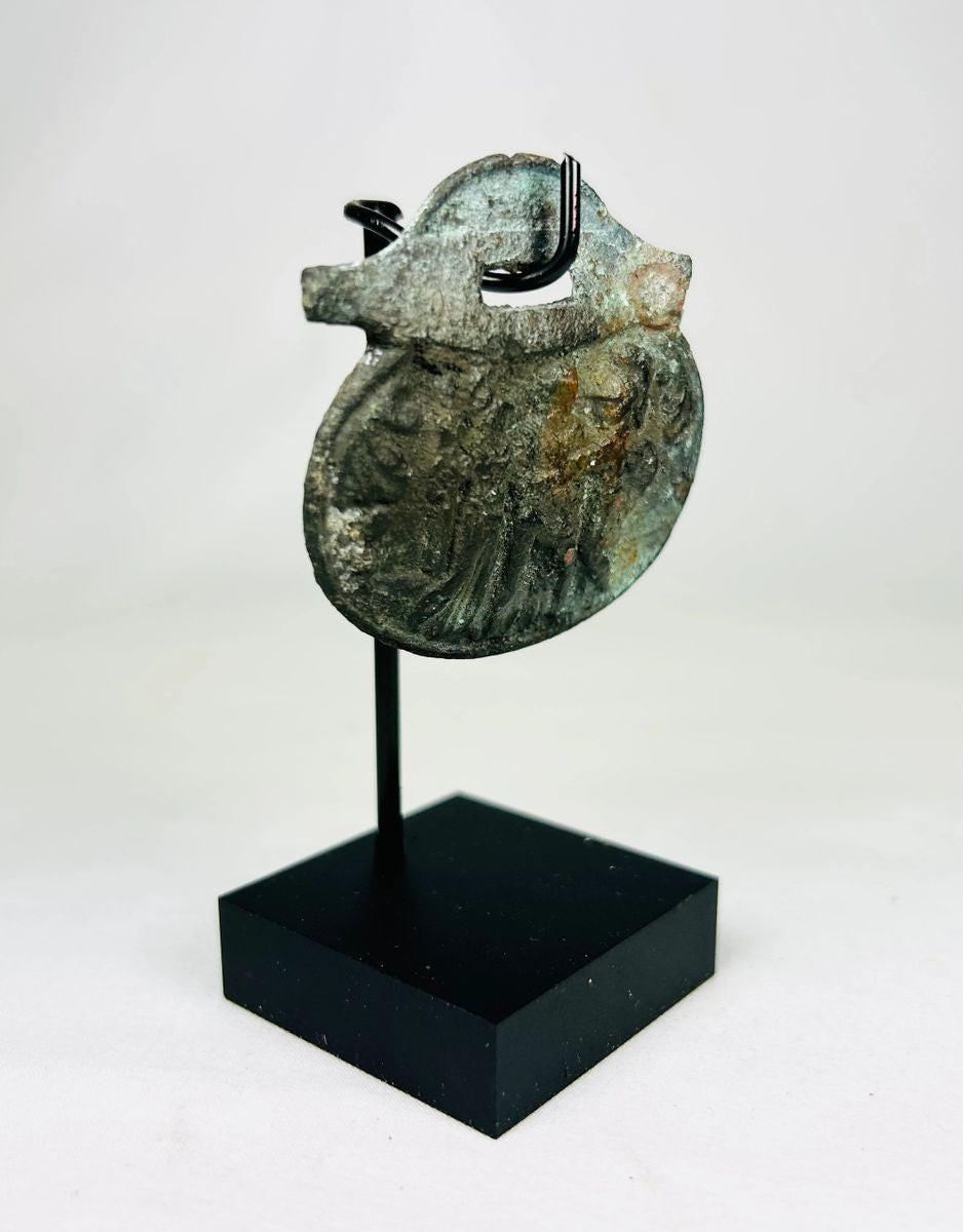 Detailed photograph of Roman bronze pendant featuring military or religious imagery.