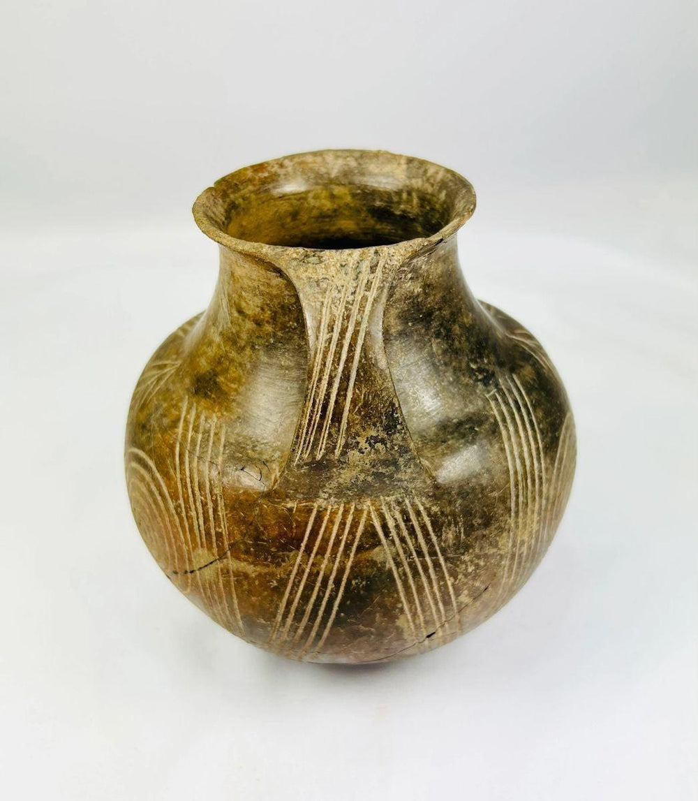 Ancient handmade pottery jug with incised geometric motifs and double handles
