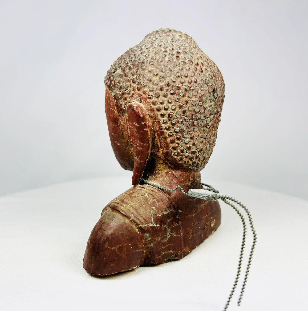 Side profile of Southeast Asian Buddha bust highlighting elongated earlobes and ushnisha.