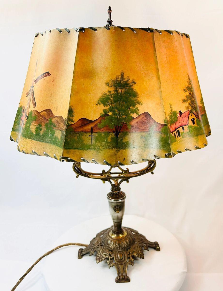 Decorative 1920s Art Nouveau table lamp with floral cast metal base and scenic parchment shade