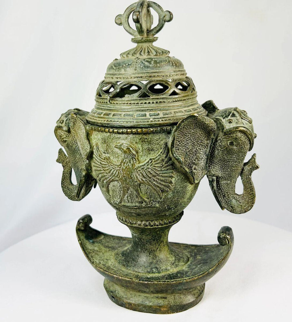 Three-quarter view of Qing Dynasty bronze censer with pierced lid, elephant handles, and crescent-shaped base.