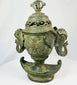 Three-quarter view of Qing Dynasty bronze censer with pierced lid, elephant handles, and crescent-shaped base.