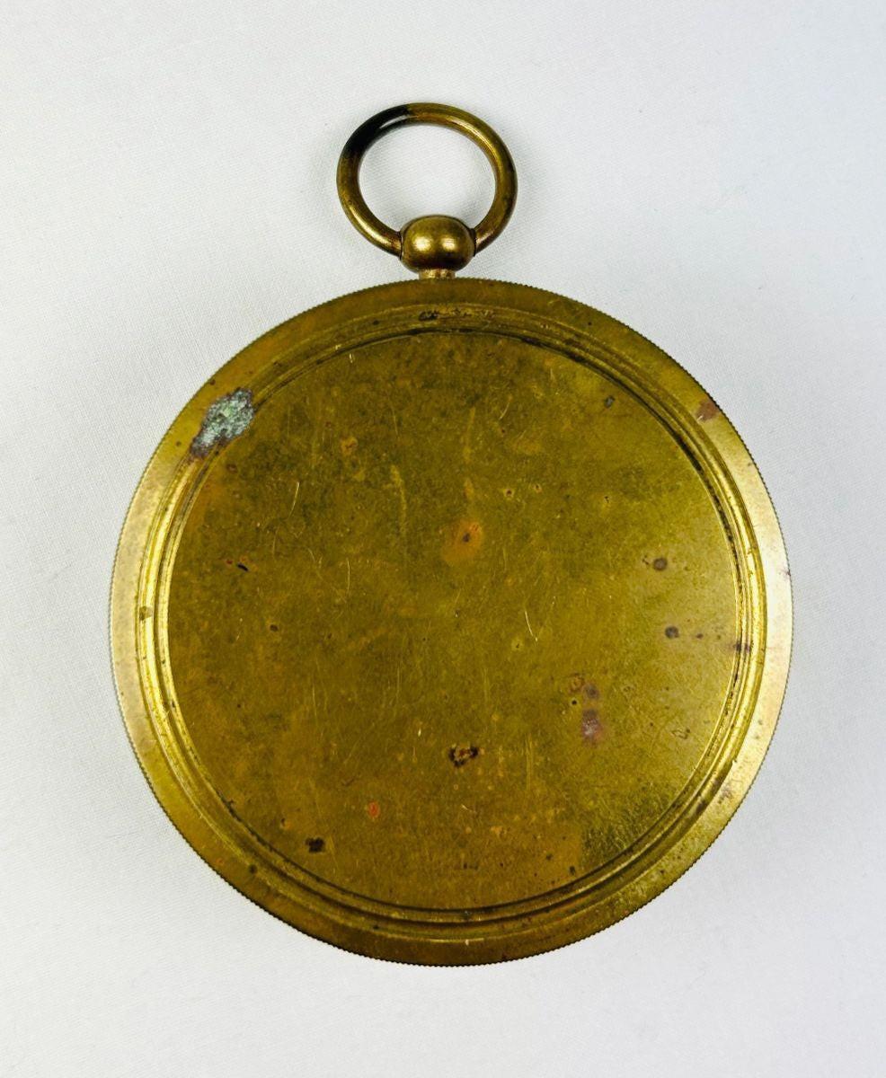Back view of a French pocket compass showing smooth brass casing and natural age patina.
