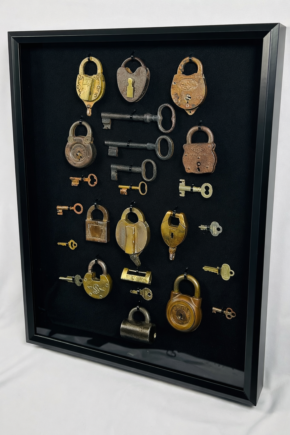 Vintage padlock collection with brass and iron locks arranged in a shadow box frame