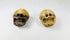 Pair of Tibetan Kapala Citipati skull beads with carved teeth and eye sockets, photographed from a forward angle on white cloth.