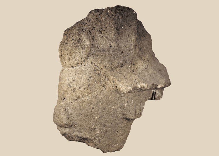 African carved stone head fragment with conical headdress on black metal display stand