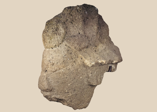African carved stone head fragment with conical headdress on black metal display stand