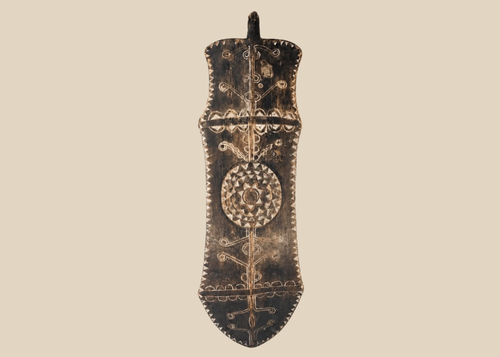 African carved wooden ceremonial shield with geometric decoration and central circular medallion