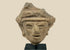Fragmentary hand-modeled terracotta head of a male figure with almond-shaped eyes, parted lips, raised headband, and stylized coiffure; Western Mexico (Nayarit, Jalisco, or Colima), Late Formative to Early Classic period, circa 200 BCE–300 CE; mounted on custom display stand.