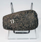 Angled view of an ancient Andean stone axe displaying its beveled edge and heavily worn archaeological surface.