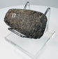 Detailed view of an ancient Ecuadorian or Peruvian ground stone axe with mottled mineral patina and surface wear.
