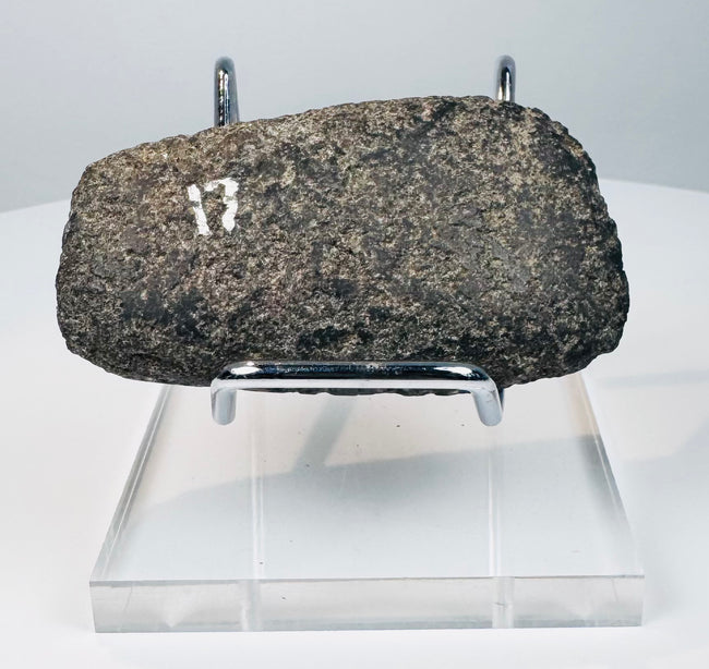 Side view of a Pre-Columbian stone axe showing its thick profile, ground surfaces, and worn cutting edge.