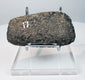 Side view of a Pre-Columbian stone axe showing its thick profile, ground surfaces, and worn cutting edge.