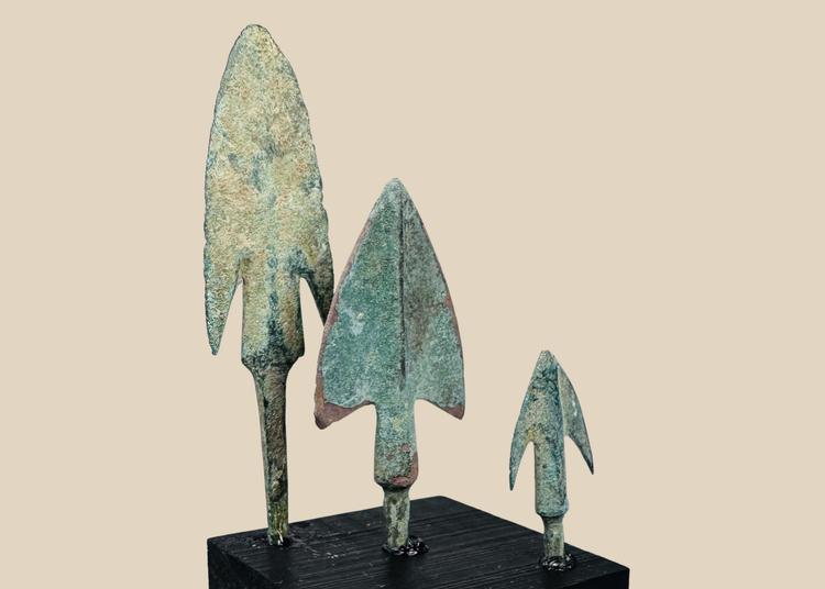 Three ancient Western Asiatic bronze projectile points mounted on a black display base