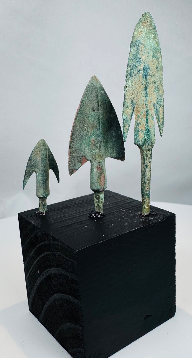 Broad triangular bronze arrowhead with pronounced shoulders and raised central rib
