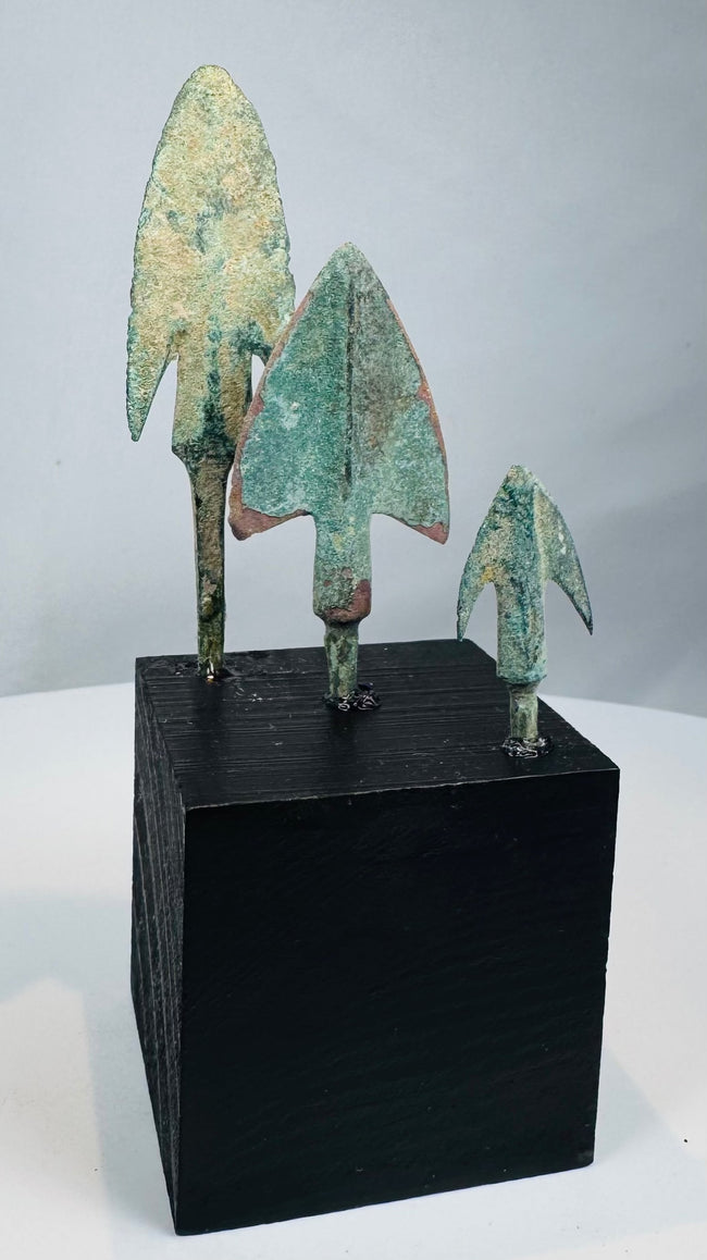 Elongated bronze projectile point with harpoon-like barbs and surviving attachment tang
