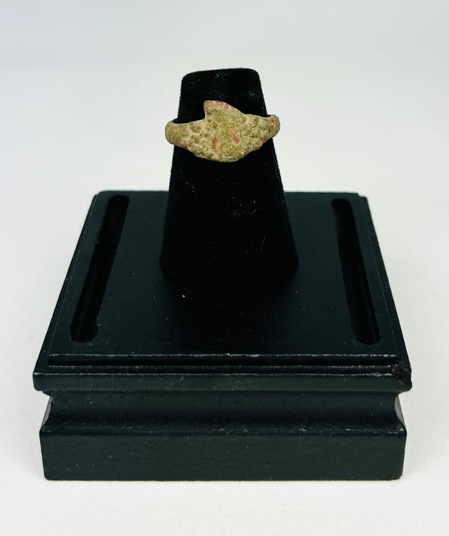 Museum-style photograph of an ancient bronze ring with natural green and brown patina