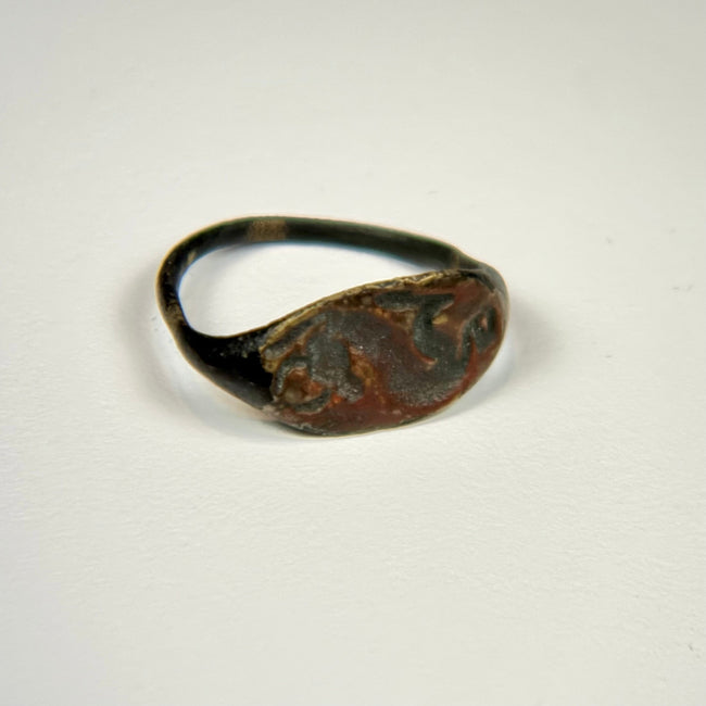 Historic bronze ring with oval animal-engraved bezel, green patination, and intact circular band