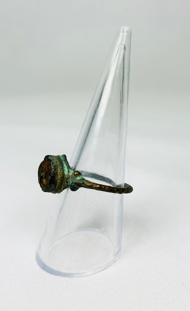 Bronze ring with encrusted surface deposits photographed on white backdrop