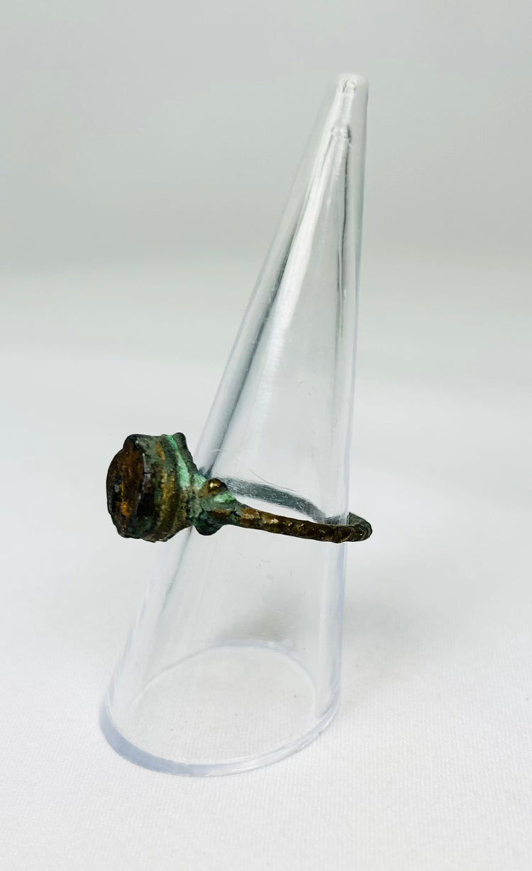 Bronze ring with encrusted surface deposits photographed on white backdrop