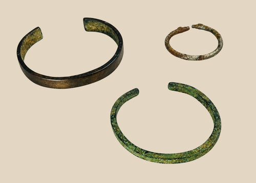 Rare set of three ancient bracelets from the Near East (Mesopotamia to Levant or Anatolia), Bronze to Iron Age (circa 6th millennium BCE – 7th century CE). Includes a broad bronze cuff with green patina, a slender oxidized bronze bracelet, and a textured iron bracelet, reflecting ancient metallurgical skill, decorative traditions, and cultural symbolism of personal adornment.