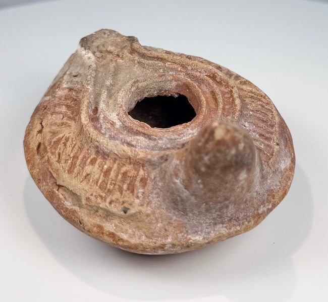 Ancient Mediterranean terracotta lamp with oval body, extended nozzle, and rear handle