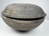 Side view of an ancient Chinese gray earthenware covered bowl with rounded lower body, fitted lid, and charcoal-gray patina.