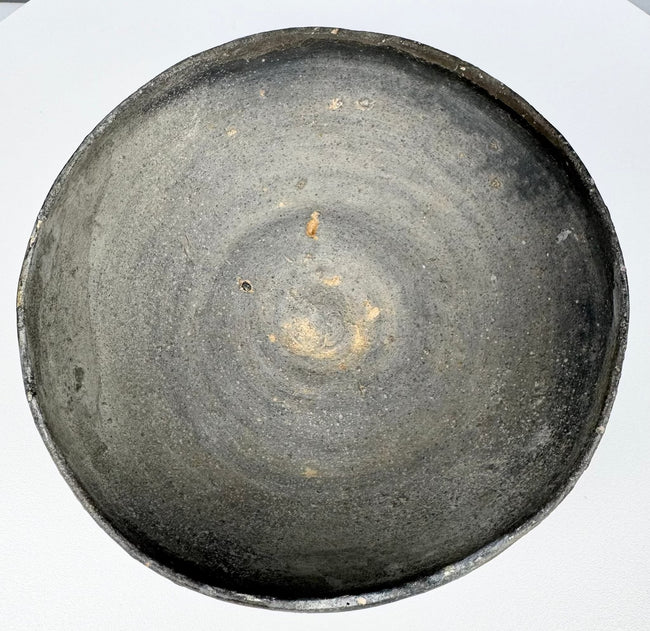 Interior of an ancient Chinese gray earthenware covered bowl showing visible concentric wheel-turning marks and lighter clay deposits.