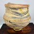 Ancient Chinese earthenware vessel displaying geometric painted motifs and mineral deposits