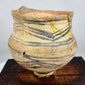 Ancient Chinese earthenware vessel displaying geometric painted motifs and mineral deposits
