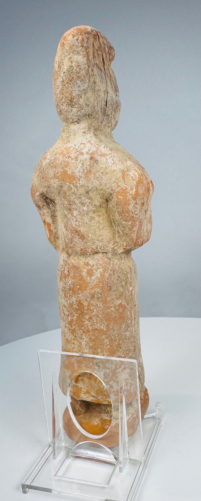 Side view of Tang tomb figure showing tall coiffure and vertical restoration crack