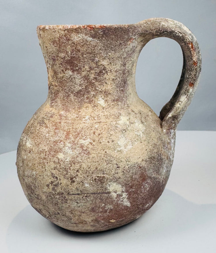 Compact ancient ceramic jug with globular belly and archaeological surface weathering