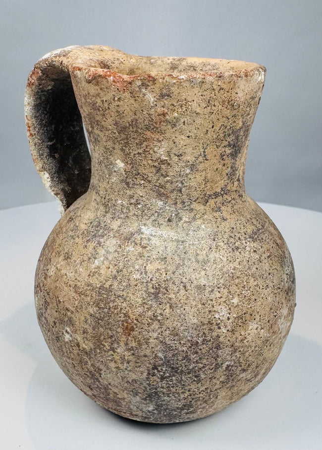 Front view of ancient pottery pitcher with narrow neck and reddish-brown clay fabric