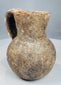 Front view of ancient pottery pitcher with narrow neck and reddish-brown clay fabric