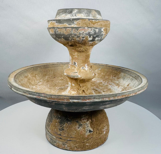 Ancient pedestal pottery vessel featuring a central raised receptacle for offerings
