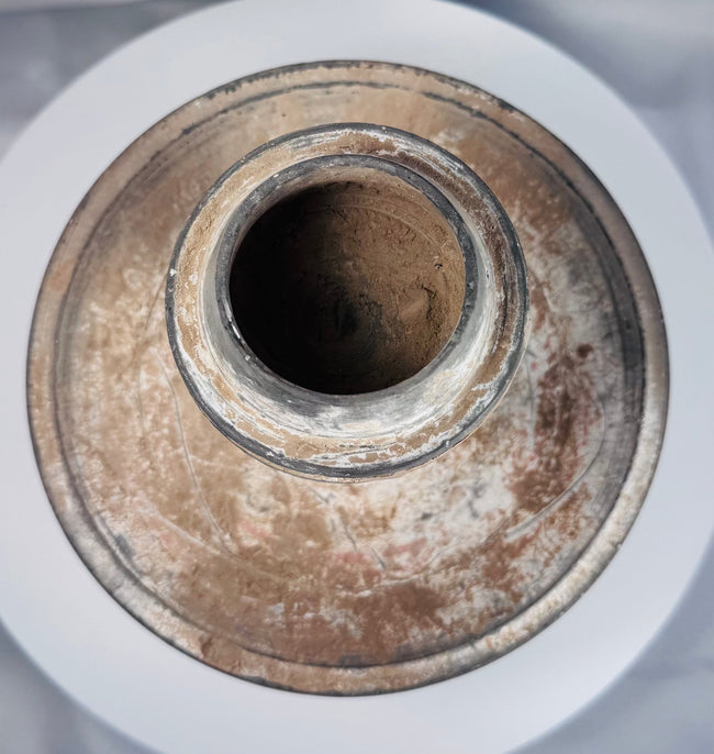 Ancient ritual pottery vessel with black painted bands and weathered surface